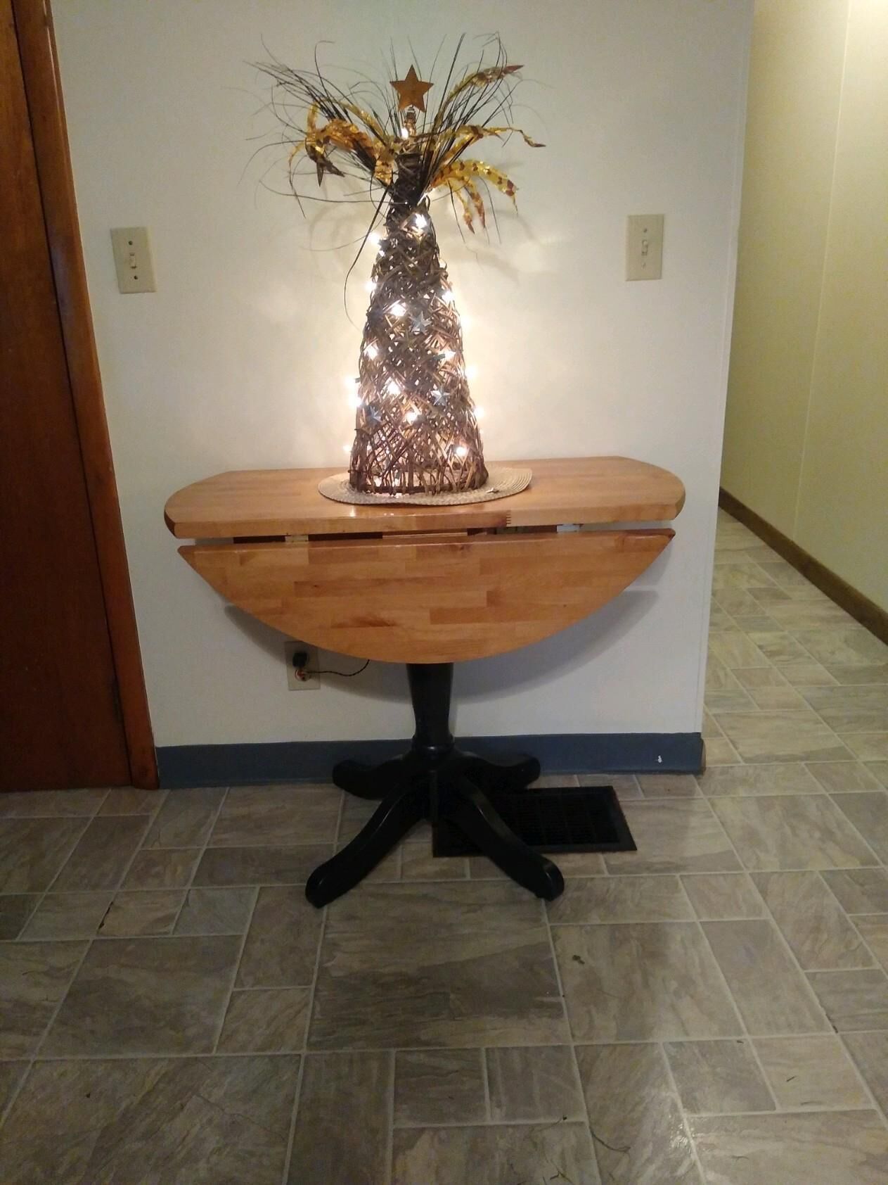 Une table en bois avec un pied noir, un vase décoratif illuminé et une étoile sur le dessus.