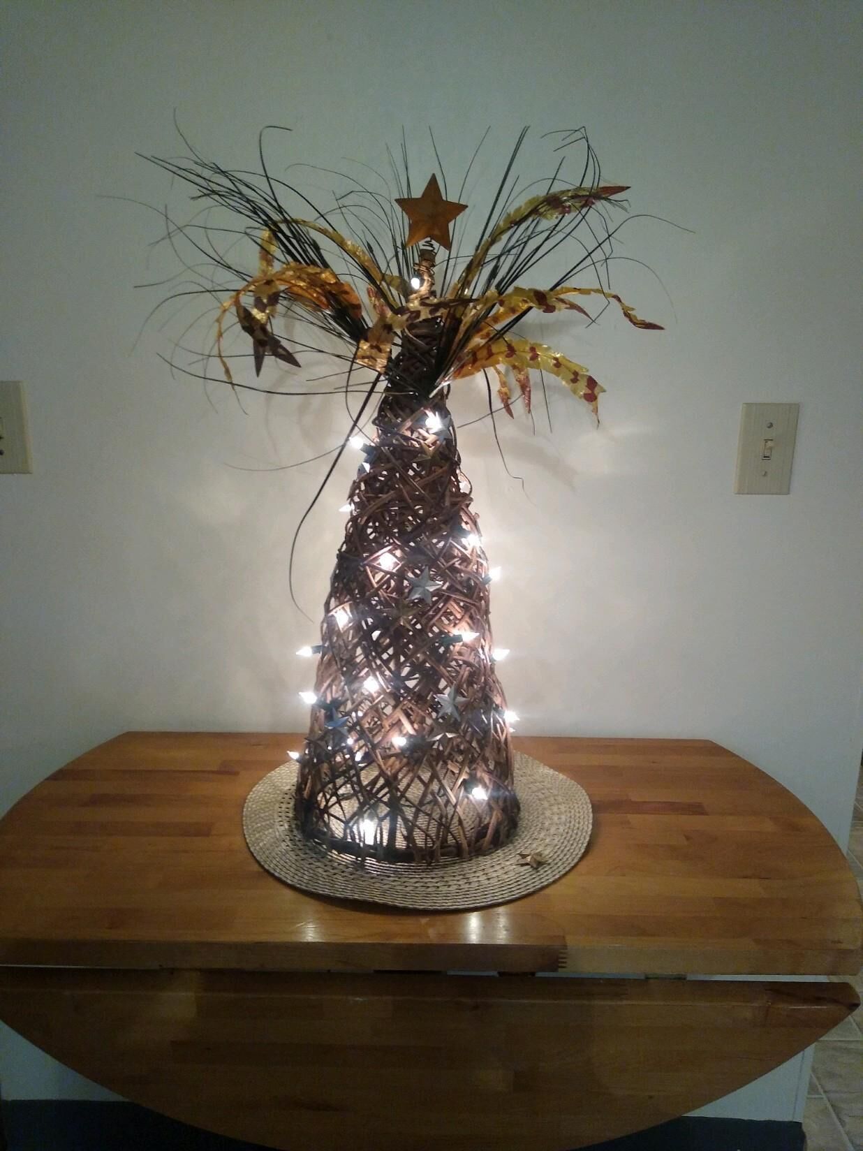 Una struttura decorativa a forma di albero con luci e una stella su un tavolo di legno.