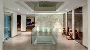 Un interior moderno con una vitrina central de cristal, pared de piedra y muebles minimalistas.