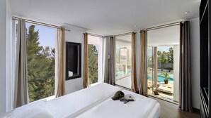 Un dormitorio con una cama grande, vistas a una piscina y un balcón con cortinas.