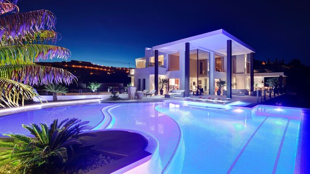 Un hotel moderno con zona de piscina, ventanas amplias y un espacio exterior bien iluminado.