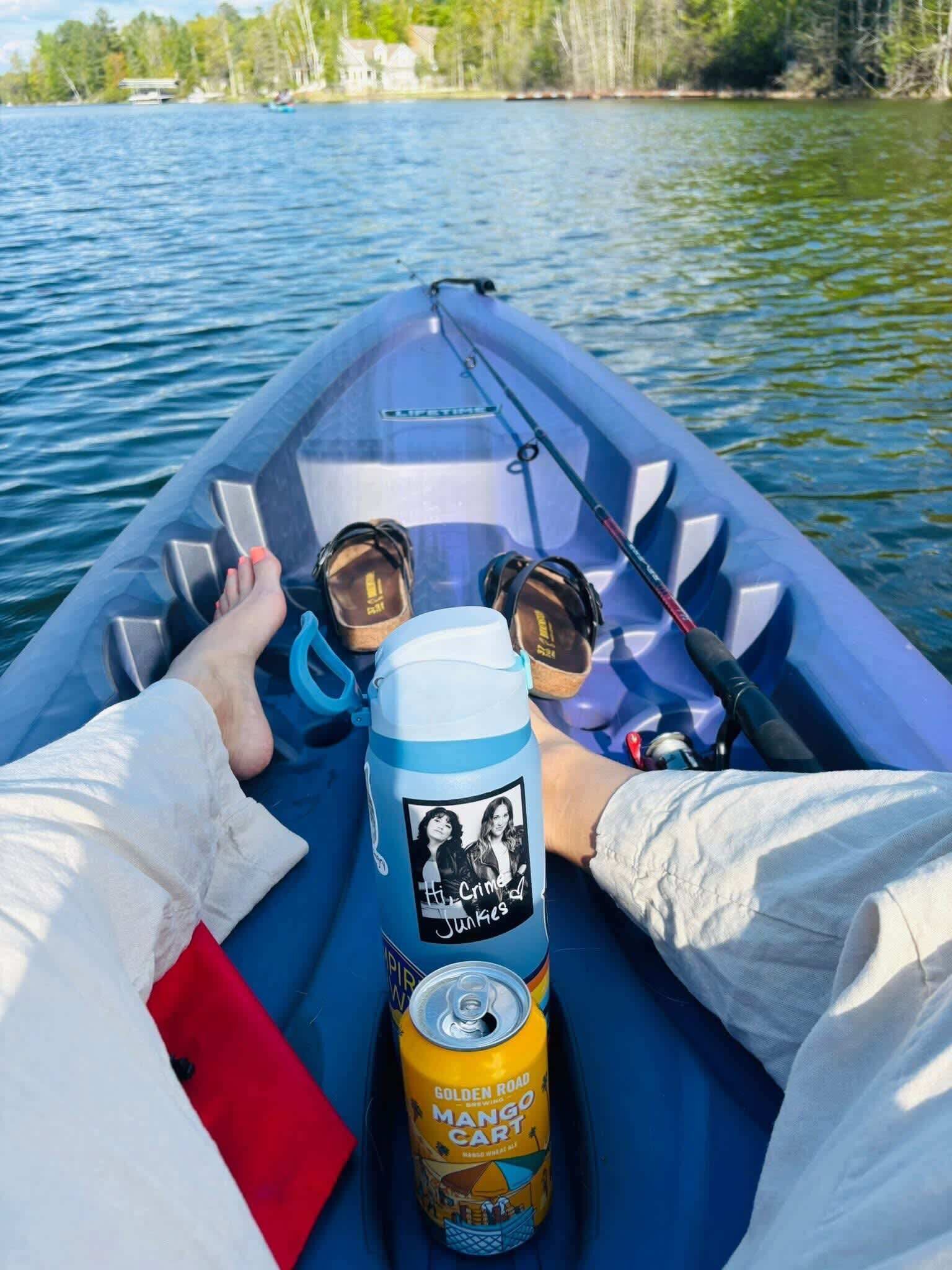 A boat with a fishing rod, a water bottle, and a can of mango juice.