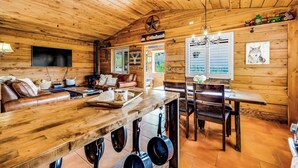 A wooden cabin interior with a dining area, kitchen, and seating space.