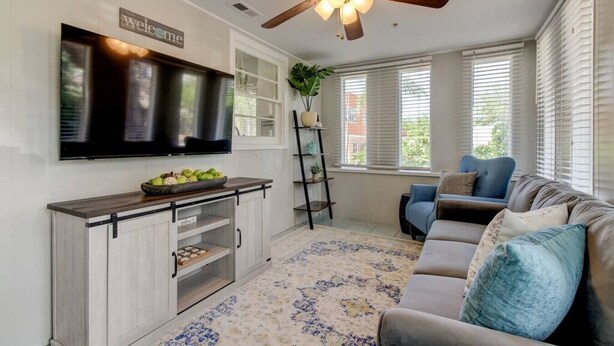 A modern living room with a flat-screen TV, a ceiling fan, a sofa, and a coffee table.