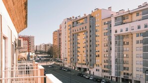 Ein mehrstöckiges Wohngebäude mit Balkonen, einer Straße davor und abgestellten Autos.