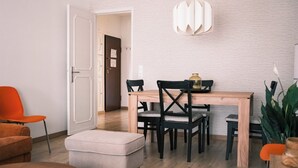 Ein Essbereich mit einem Holztisch, schwarzen Stühlen, einer Hängeleuchte und einer Tür zu einem anderen Raum.