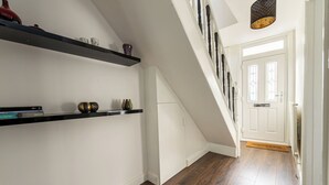 Una escalera con una puerta blanca al final, suelo de madera y estantes negros flotantes decorados con objetos.
