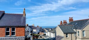A coastal town with terraced houses, a prominent chimney, and a clear view of the sea.