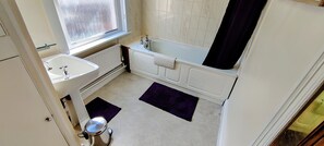A bathroom with a sink, bathtub, and a window.
