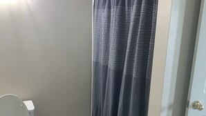 Une salle de bain avec des toilettes, un rideau de douche et un tapis marron.