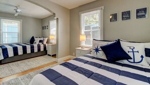 Un dormitorio con cama, mesita de noche, lámpara y ventana con persianas.