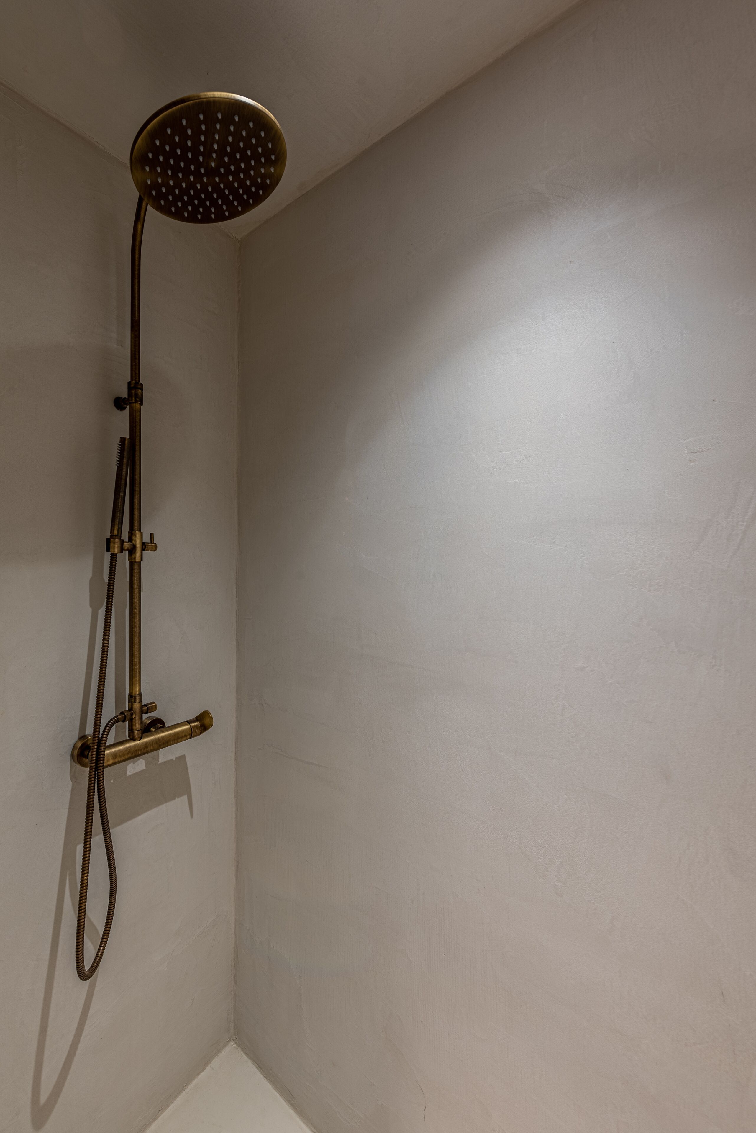 A shower with a handheld head and a handheld hose.