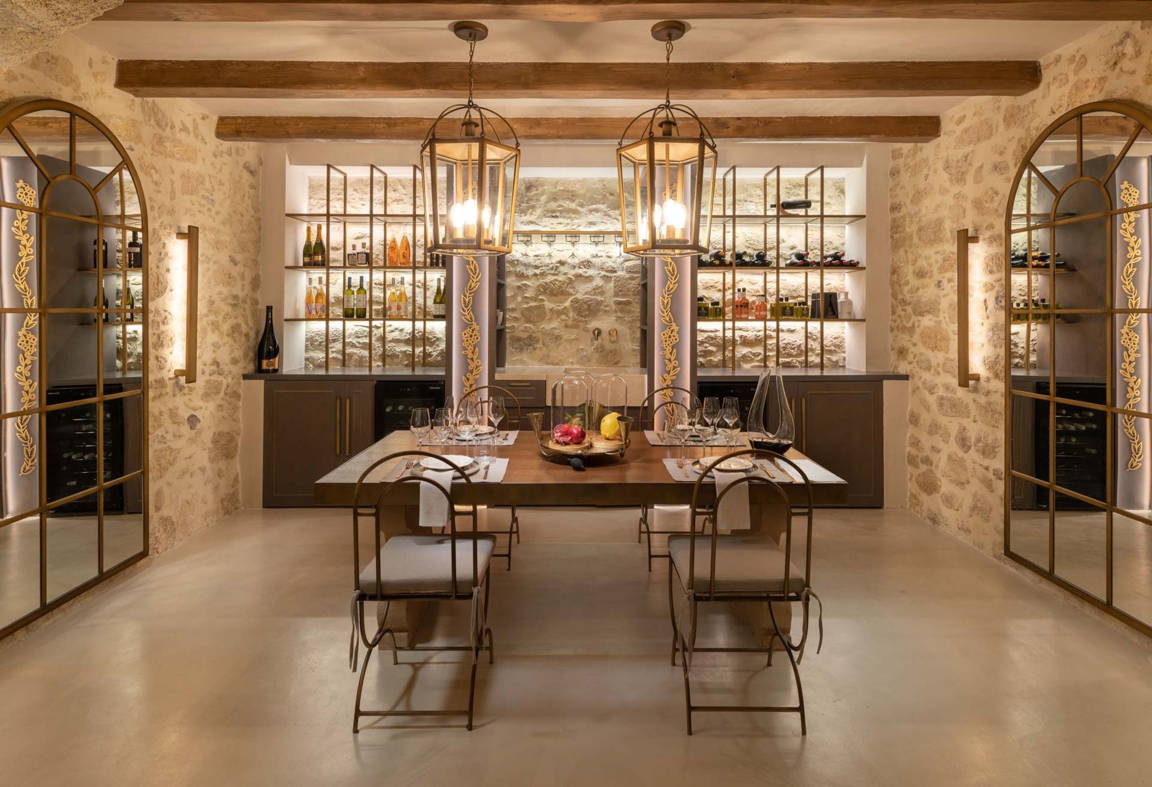 A dining area with a stone wall, a wooden ceiling, and a bar with shelves of bottles.