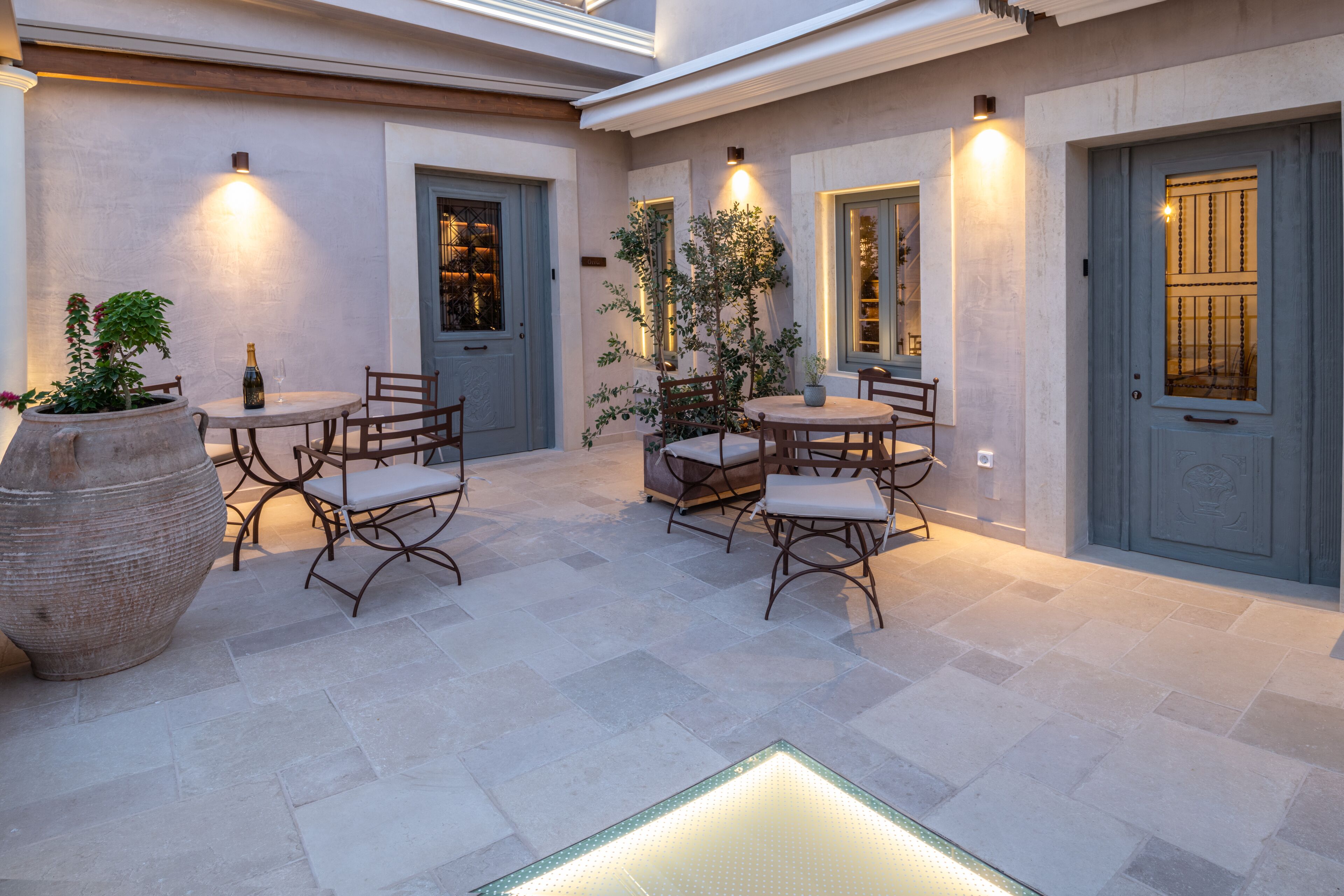 A courtyard with outdoor seating, a large planter, and a wine bottle.