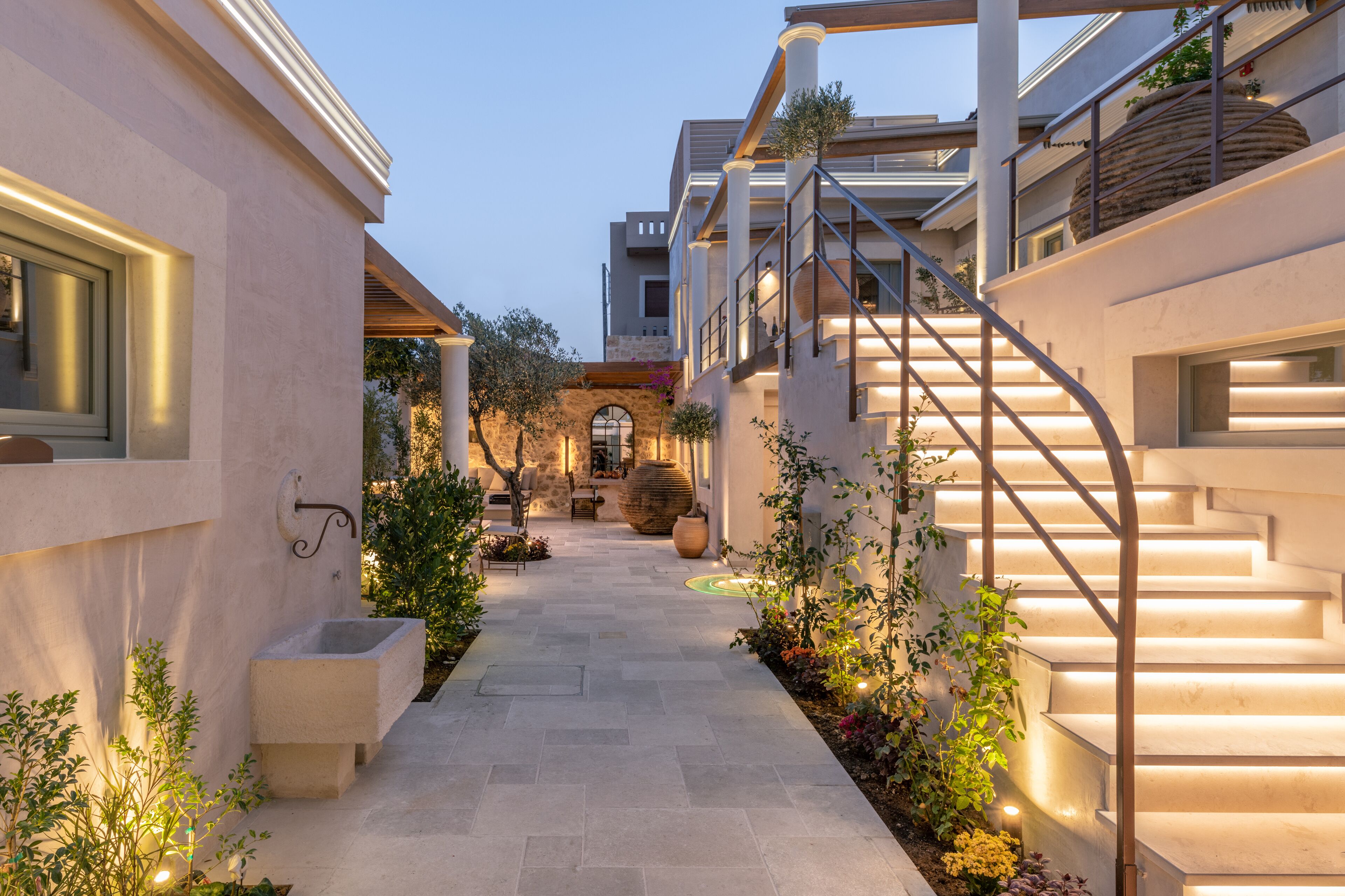 A modern building with a central courtyard, stone pathway, and a staircase leading to an upper level.