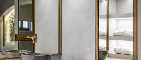 Un baño moderno con un espejo grande, dos lavabos de piedra y artículos de aseo ordenados.