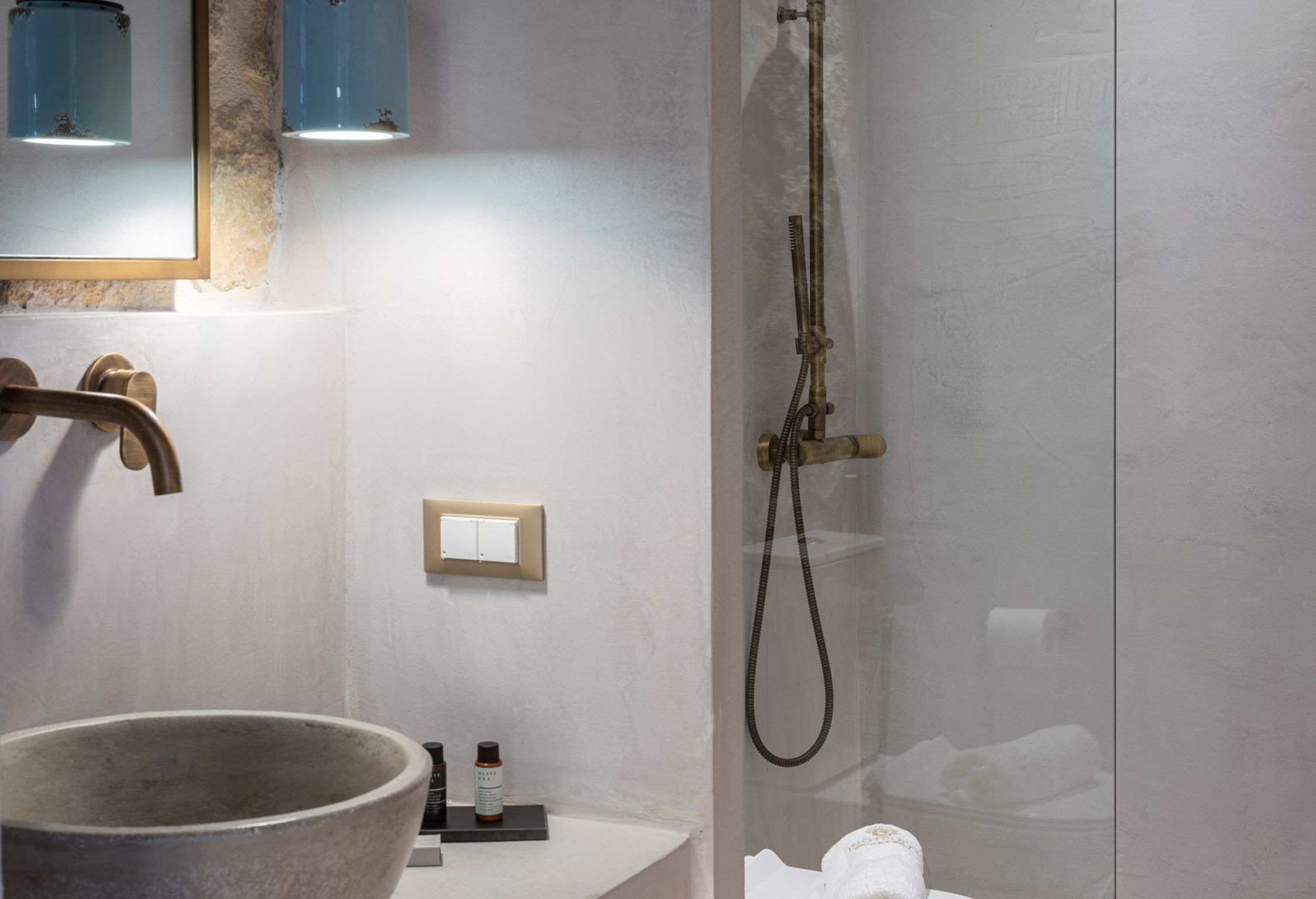 A modern bathroom with a large stone sink, a handheld showerhead, and a glass-enclosed shower.