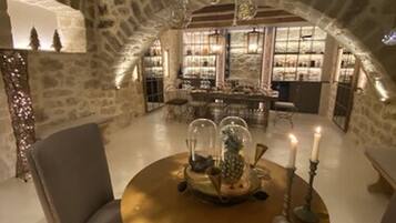 Un espace repas avec une table ronde, des chaises, un lustre et un mur en pierre en arrière-plan.