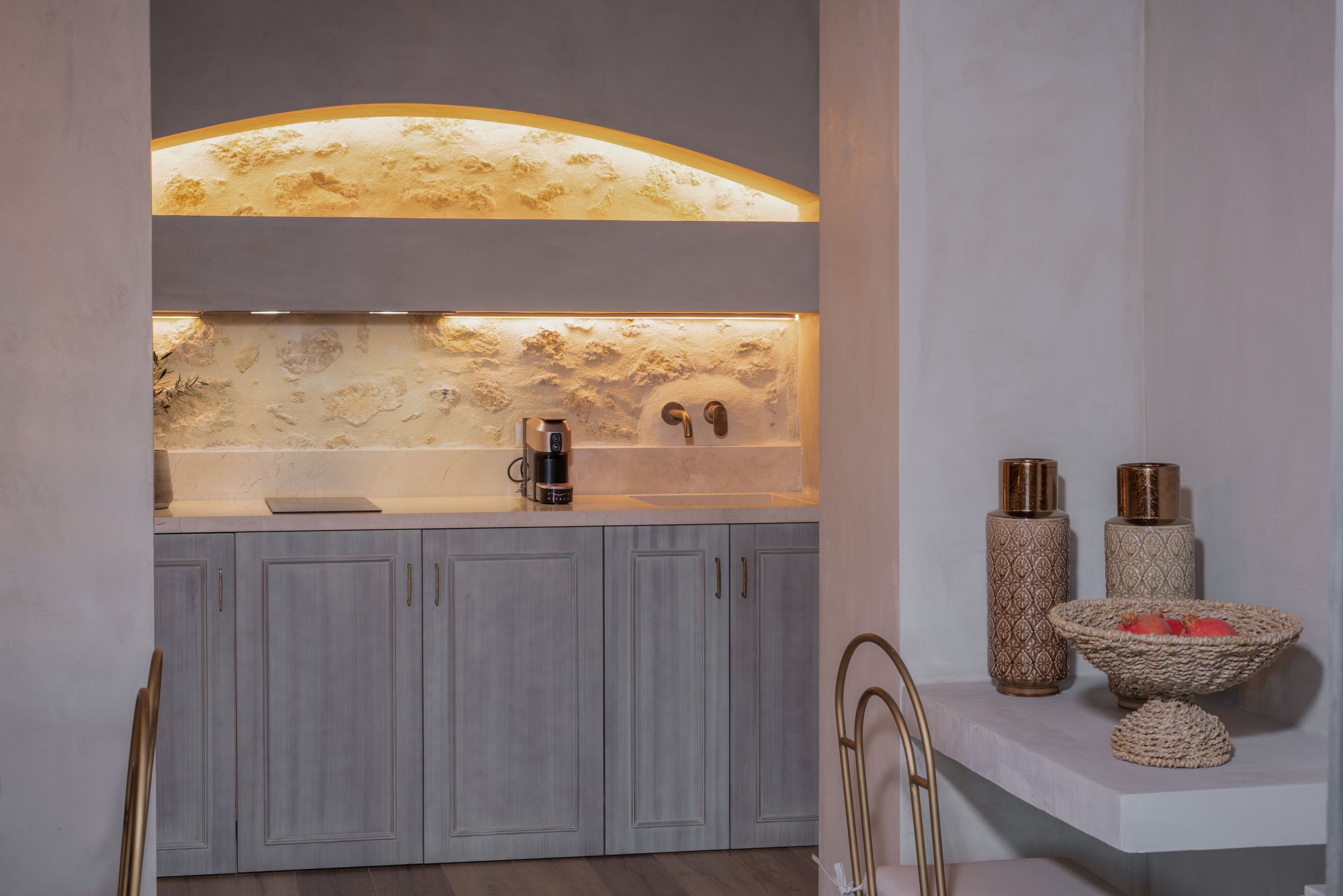 A modern kitchen with a marble backsplash, a coffee machine, and decorative vases.