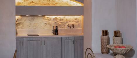A modern kitchen with a marble backsplash, a coffee machine, and decorative vases.