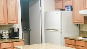 Eine Küche mit Holzausstattung, einem weißen Kühlschrank, einer Kaffeemaschine und einer Arbeitsplatte aus Granit.