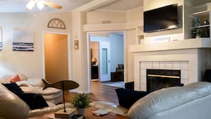 Ein Wohnzimmer mit Kamin, einem darüber montierten Fernseher und einer Couch.