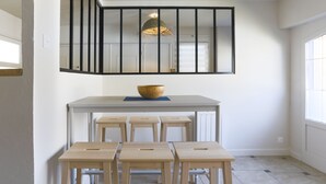 Et køkken med en central ø, barstole, en hængende lampe og et vindue.