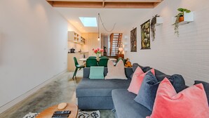 Ett modernt vardagsrum med en grå soffa, ett soffbord och en matplats med gröna stolar.