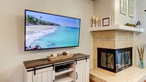 Un televisor de pantalla plana montado en la pared sobre un mueble de madera con chimenea abajo.
