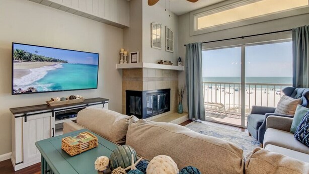 Una sala de estar con televisor, sofá y balcón con vista a la playa.