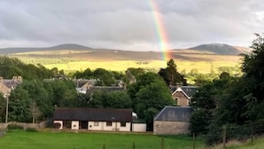 Un paysage rural avec un arc-en-ciel, des maisons et un champ.