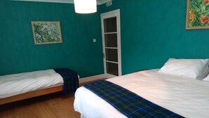 Une chambre avec deux lits, un plancher en bois, des murs de couleur turquoise et une porte avec un panneau de verre.