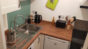 Une cuisine compacte équipée d’un évier, d’une machine à café, d’un grille-pain et d’un lave-vaisselle.