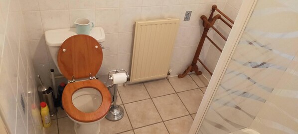 A bathroom with a wooden toilet, a radiator, and a towel rack. - Ardvonie House (Kingussie)