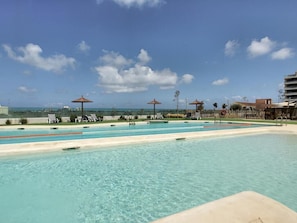 Ein Schwimmbecken mit klarem Wasser, Liegestühlen und Sonnenschirmen.