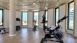 A spacious gym with wooden flooring, large windows, and various exercise equipment. - Dreamy Sunset - Appartement (Playa Honda)