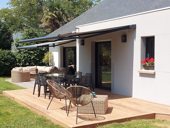 An outdoor patio with a covered seating area, a dining table, and wicker chairs.