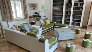 Una sala de estar con un sofá, un reposapiés y una estantería.