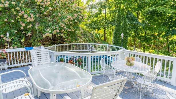 A covered outdoor deck with white metal furniture, a glass table, and a white fence. - High Street Hideaway (New Milford)