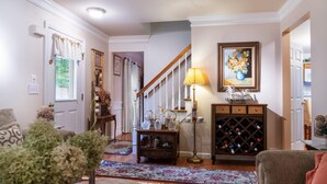 A well-lit hallway with a wooden staircase, a wine rack, and a floral painting on the wall. - High Street Hideaway (New Milford)