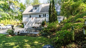 A two-story house with a covered porch, a staircase, and a car parked in the driveway. - High Street Hideaway (New Milford)