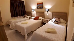 A hotel room with two single beds, each with a pillow and a folded towel. There are bedside tables with lamps and a painting on the wall. - Superb & comfortable 2-bedroom villa apt sleeps 5, swimming pool, AC/WiFi (Il-Mellieħa)
