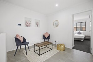 Relax in this stylish room with a central coffee table, two comfortable chairs, and a large window.