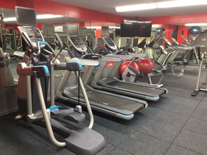 Een sportschool met loopbanden, krachtapparaten en fitnessballen.