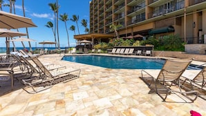 A hotel pool area with lounge chairs, a pool, and a building with multiple balconies. - Mana Kai 404, Beautifully Renovated, Unbelievable Ocean View (Kihei)