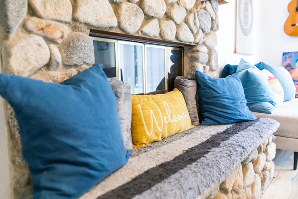 A stone fireplace with a glass door, surrounded by blue and yellow pillows. - 3bd/2.5bath house+Ocean Views,Spa, Sauna,Fire Pit & Huge backyard (San Juan Capistrano)
