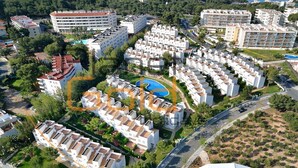 Luchtbeeld van een resort met meerdere witte gebouwen, een zwembad en een weg met voertuigen.