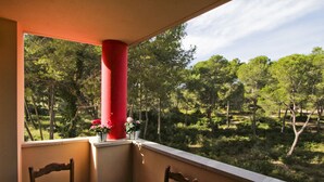 Un balcón con mesa y sillas, con vista a un área boscosa.