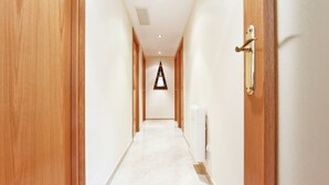 Un pasillo con puertas de madera a ambos lados, un radiador a la derecha y un letrero triangular en la pared.