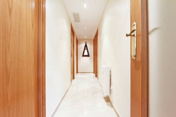 A hallway with wooden doors on both sides, a radiator on the right, and a triangular sign on the wall.